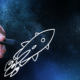 hand drawing a rocket ship zooming across space